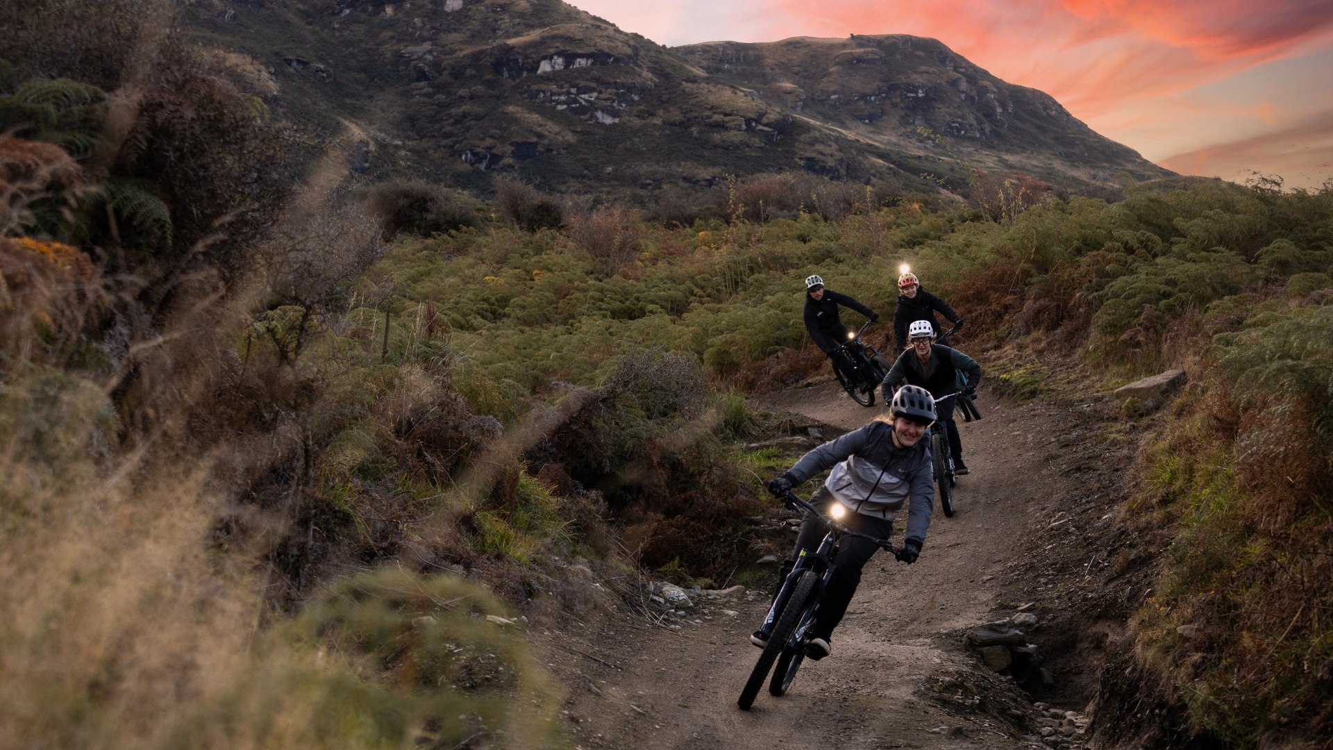 4 riders on Bike Glendhu MTB Trail during pink sunset in Wanaka, NZ